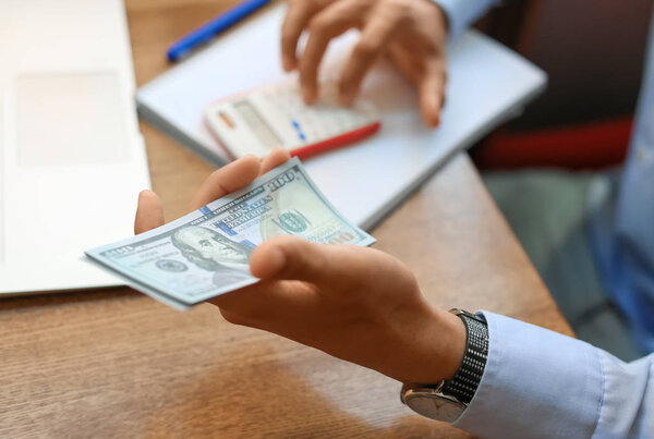 Афроамериканец считает сбережения за столом, крупным планом
