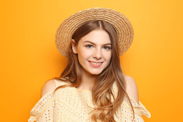 Beautiful young woman with hat on color background