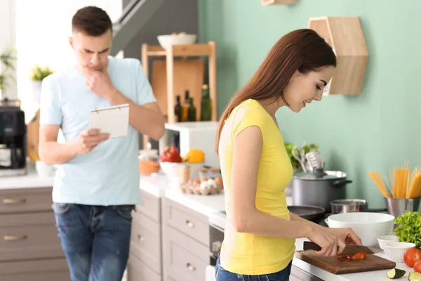 Jovem Cozinhando Enquanto Seu Marido Lendo Livro Receitas Cozinha — Fotografia de Stock