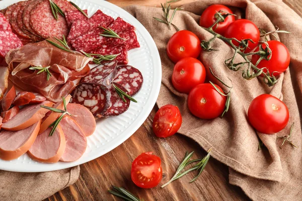 Plate with assortment of delicious deli meats on table