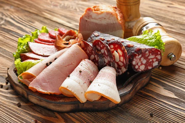 Assortment of delicious deli meats on wooden board