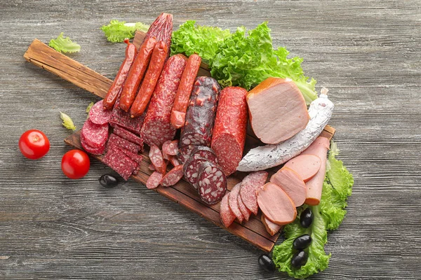 Assortment of delicious deli meats on wooden board