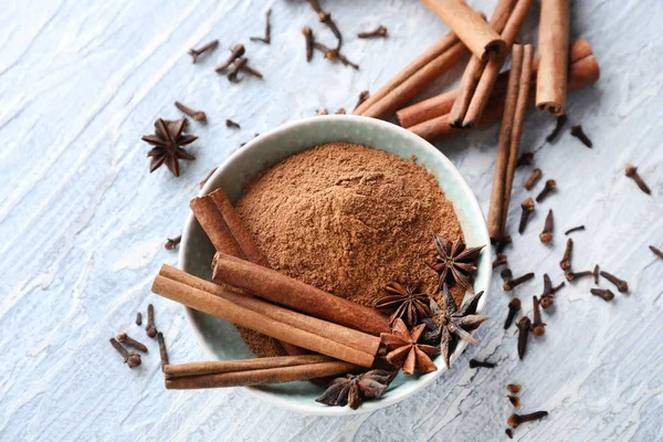 Bowl with cinnamon and spices on wooden background