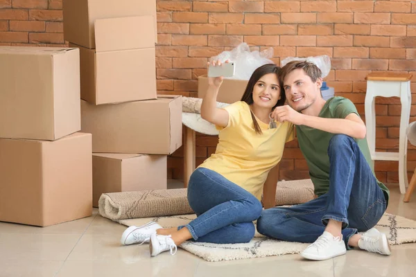 Joven Pareja Feliz Tomando Selfie Con Llave Nueva Casa Interior — Foto de Stock