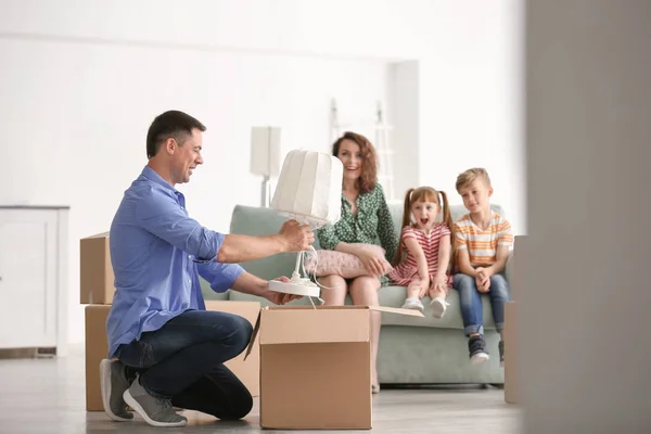 Man Unpacking Box While His Family Sitting Sofa Indoors Moving — Stock Photo, Image