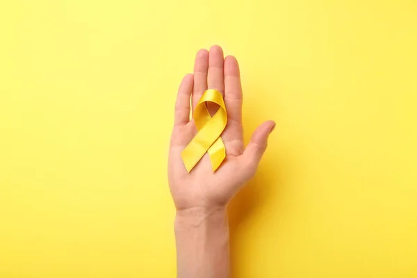 Femmina Mano Tenendo Nastro Giallo Sfondo Colore Concetto Cancro — Foto Stock