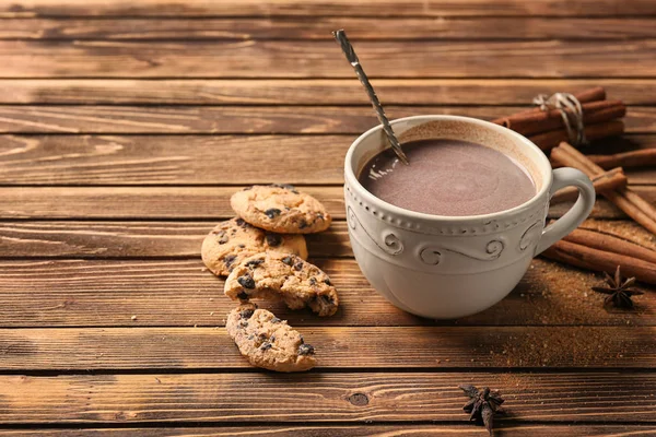 Cup of delicious hot cocoa and cookies on wooden background