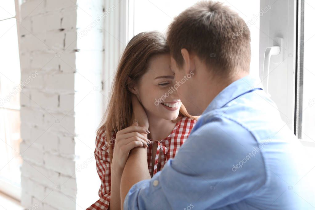 Happy young couple resting near window at home