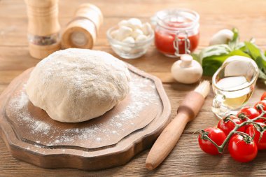 Çiğ hamur ve malzemeler ahşap arka plan üzerinde pizza ile kompozisyon