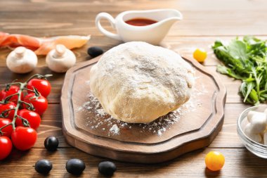 Çiğ hamur ve malzemeler ahşap arka plan üzerinde pizza ile kompozisyon