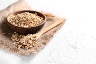 Kase ve kaşık ışık arka plan üzerinde çiğ yulaf ezmesi ile