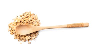 Kaşık ve beyaz arka plan üzerinde çiğ yulaf ezmesi yığını