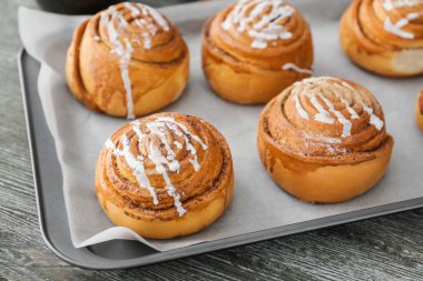 Ahşap zemin, closeup üzerine lezzetli tarçınlı çörek ile tepsi