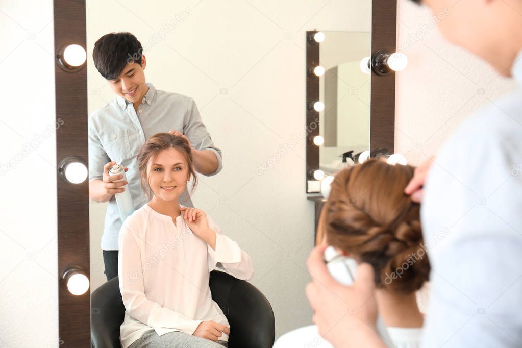 Professional hairdresser working with client in beauty salon