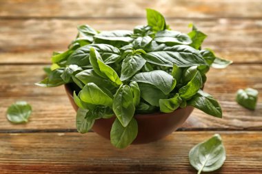 Ahşap arka planda taze yeşil fesleğenli kase