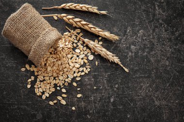 Koyu arka plan üzerinde çiğ yulaf ezmesi ile çuval