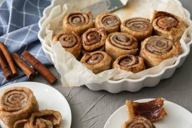 Pişirme çanağı ve masada lezzetli tarçınlı çörek ile plakalar