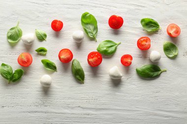 Kompozisyon ile taze fesleğen yaprakları, domates ve mozzarella ahşap arka plan üzerinde