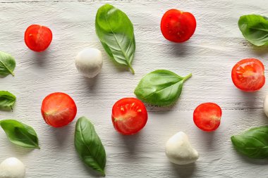 Kompozisyon ile taze fesleğen yaprakları, domates ve mozzarella ahşap arka plan üzerinde