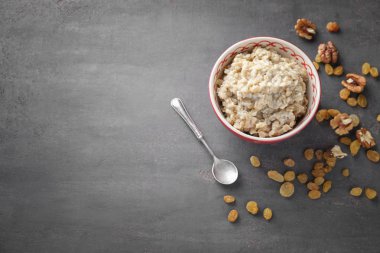 Lezzetli yulaf ezmesi, üzüm ve gri arka plan üzerinde ceviz ile kase