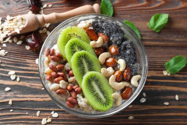 Fındık ve ahşap masa üzerinde kivi lezzetli yulaf ezmesi ile kase