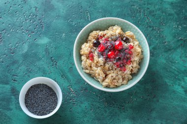 Kase lezzetli yulaf ezmesi, çilek ve dokulu renkli arka plan üzerinde haşhaş tohumu