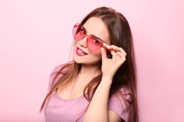 Renk arka plan üzerinde kalp şeklinde gözlüklü genç kadın