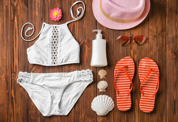 Swimming suit and beach accessories on wooden background