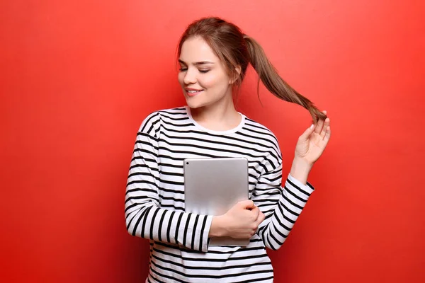 Beautiful young woman with tablet PC on color background