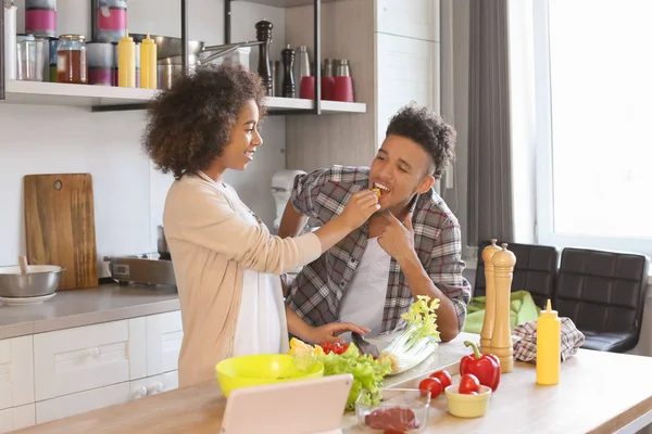 年轻的非洲裔美国人情侣在厨房里一起做饭时品尝食物 — 图库照片