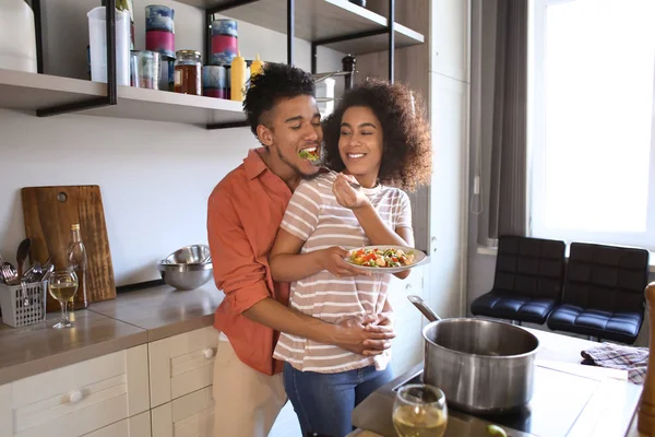 年轻的非洲裔美国人情侣拥抱和品尝厨房的食物 — 图库照片