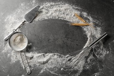 Dağınık un ve gri arka plan üzerinde mutfak eşyaları ile kompozisyon