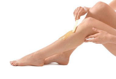Young woman epilating her leg with liquid sugar on white background clipart