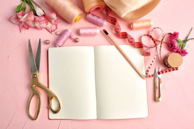 Defter, renk konu ve dokulu renkli arka plan üzerinde dikiş aksesuarları ile kompozisyon