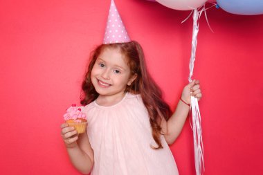 Balonlar ve cupcake renk arka plan üzerinde sevimli küçük kız. Doğum günü kutlaması