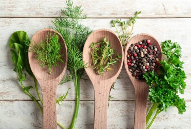 Kaşık ile farklı taze otlar ve baharatlar ahşap arka plan üzerinde