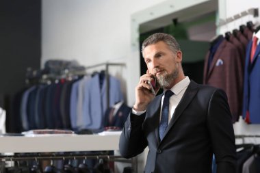 Erkek giyim mağazasında cep telefonunda şık uymak yakışıklı olgun adam