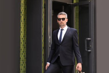 Mağaza açık havada yakınındaki alışveriş torbaları ile takım elbiseli Olgun yakışıklı