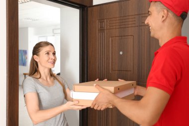Kapı kadına pizza kutuları veren genç adam. Gıda dağıtım hizmeti