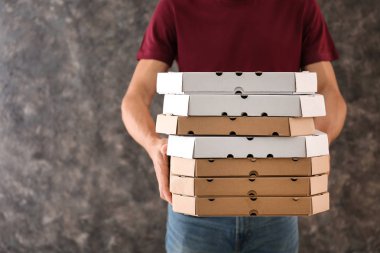 Pizza kutuları grunge arka plan üzerinde olan genç adam. Gıda dağıtım hizmeti