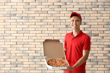 Lezzetli pizza kutusu tuğla duvara tutan genç adam. Gıda dağıtım hizmeti