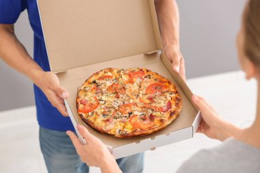 Genç adam lezzetli pizza kutusu kapalı kadın için veriyor. Gıda dağıtım hizmeti