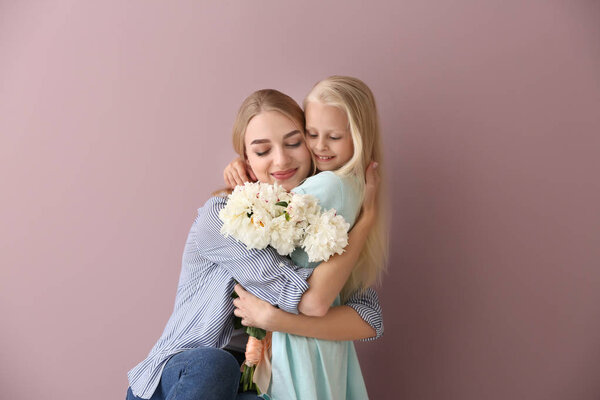 Привлекательная молодая женщина и милая маленькая девочка с красивыми цветами на цветном фоне
