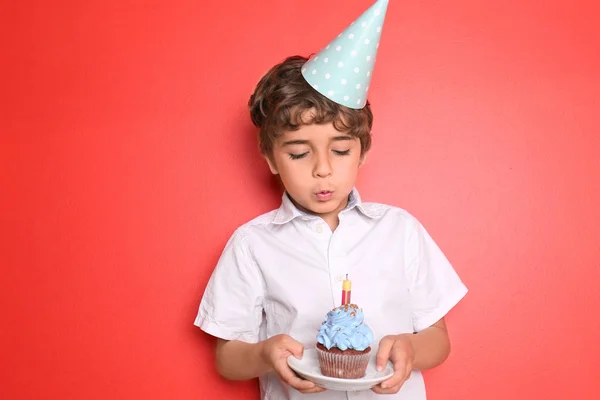 Menino Soprando Vela Aniversário Cupcake Contra Fundo Cor — Fotografia de Stock