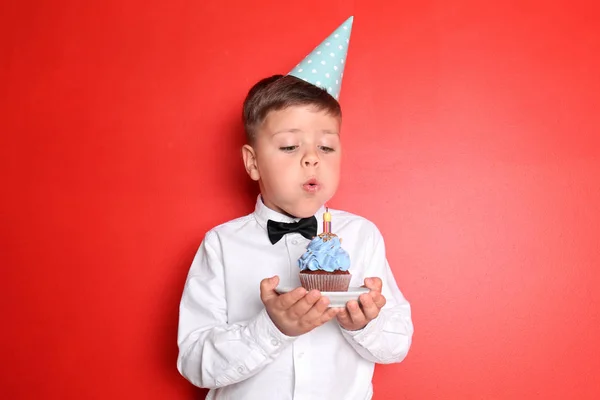 Menino Soprando Vela Aniversário Cupcake Contra Fundo Cor — Fotografia de Stock