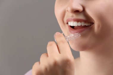 Oklüzal splint gri arka plan üzerinde closeup ağzına koyarak kadın