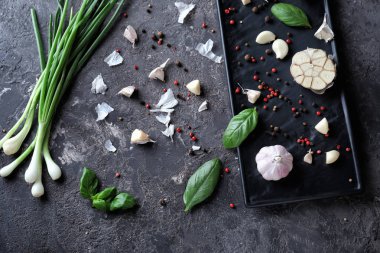 Taze sarımsak, soğan ve baharat karanlık dokulu arka plan üzerinde plaka