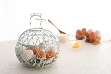 Mutfak masasının üstünde metal sepet tavuk ve yumurta