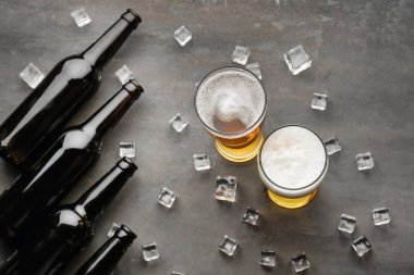 Lezzetli bira buz küpleri ve gri arka plan üzerinde şişe bardak