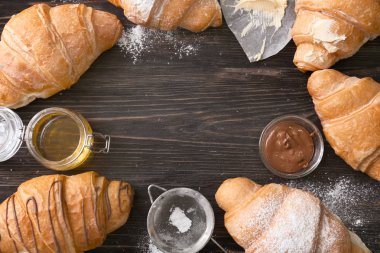 Lezzetli kruvasan ve ürünleri ahşap arka plan üzerinde çerçeve yaptı